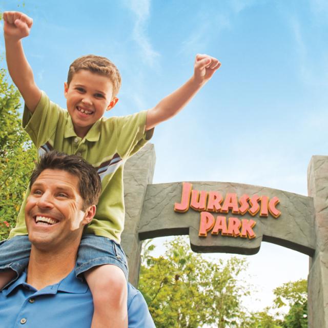 Universal's Islands of Adventure father and son posing in front of the Jurassic Park sign