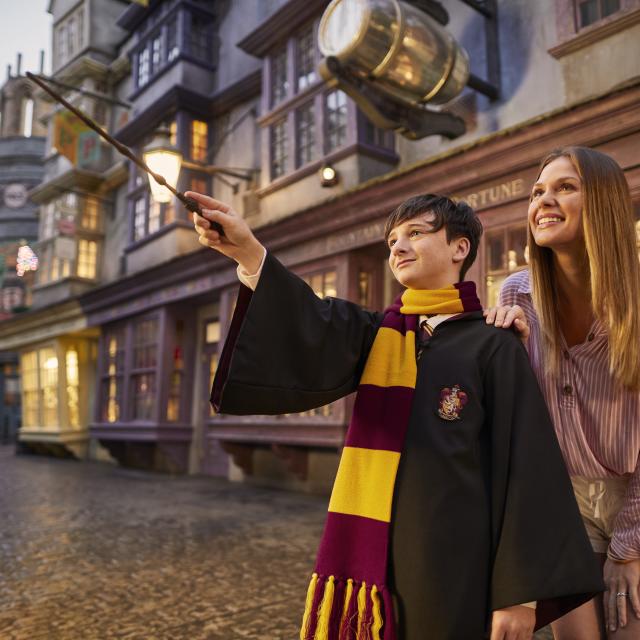 boy dressed as Harry potter waves wand while mom watches