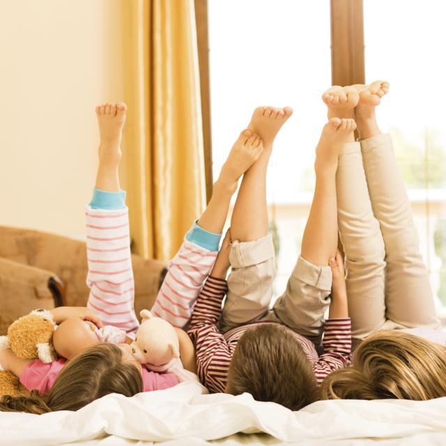 Children lying down on a bed with legs in the air