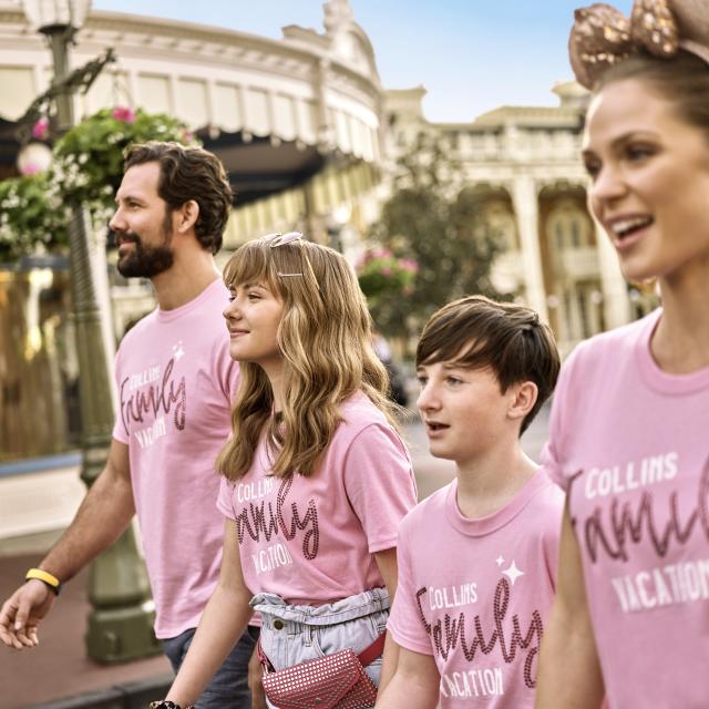 A family of four, in matching pink shirts, walking on Main Street at the Magic Kingdom in the Walt Disney World Resort.