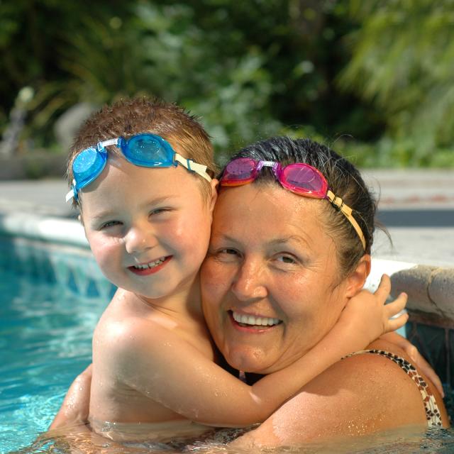A grandmother and her grandson hugging in a swimming pool
