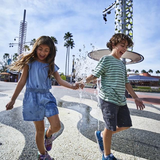 Siblings walking across a splash pad at Universal CityWalk Orlando