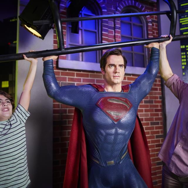 A father and son posing with Superman at Madame Tussauds in ICON Park.